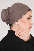 Woman wearing a brown headscarf against a plain background